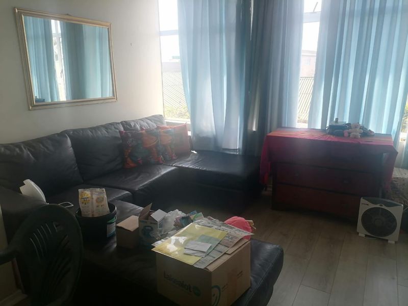 A living room area featuring laminate flooring and large windows that provide natural light.