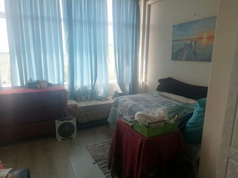 A bedroom featuring laminate flooring and a large window that allows for ample natural light.