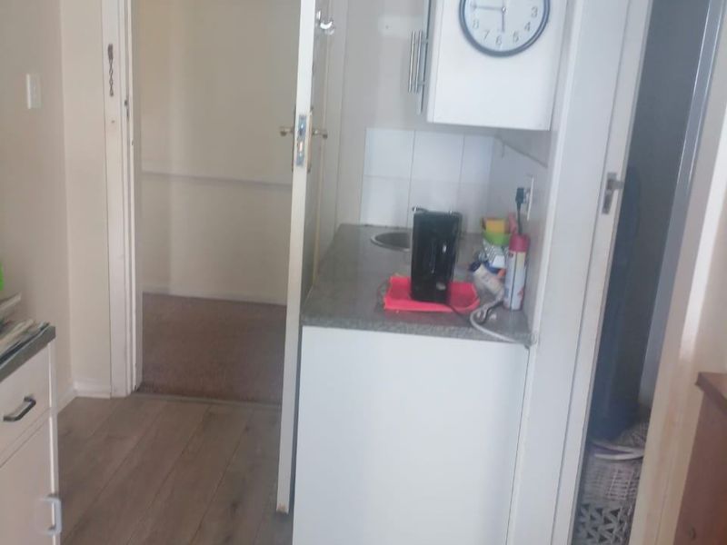 A compact scullery or kitchenette area featuring built-in cabinetry, a sink, and laminate flooring, providing functional utility space within the apartment.