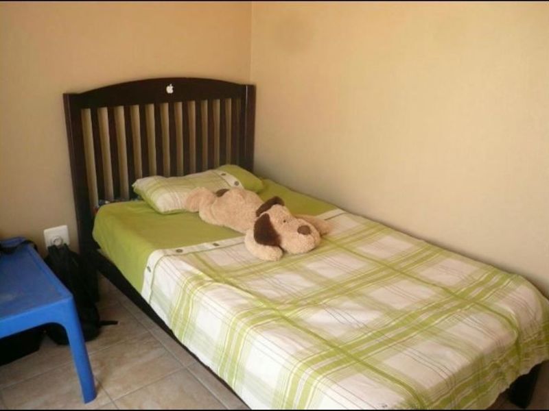 A compact bedroom featuring tiled flooring and neutral wall paint, suitable for a single bed setup.