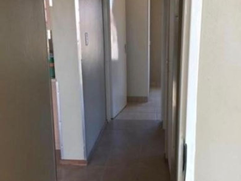 A functional hallway connecting multiple rooms, featuring neutral wall tones and tiled flooring throughout.