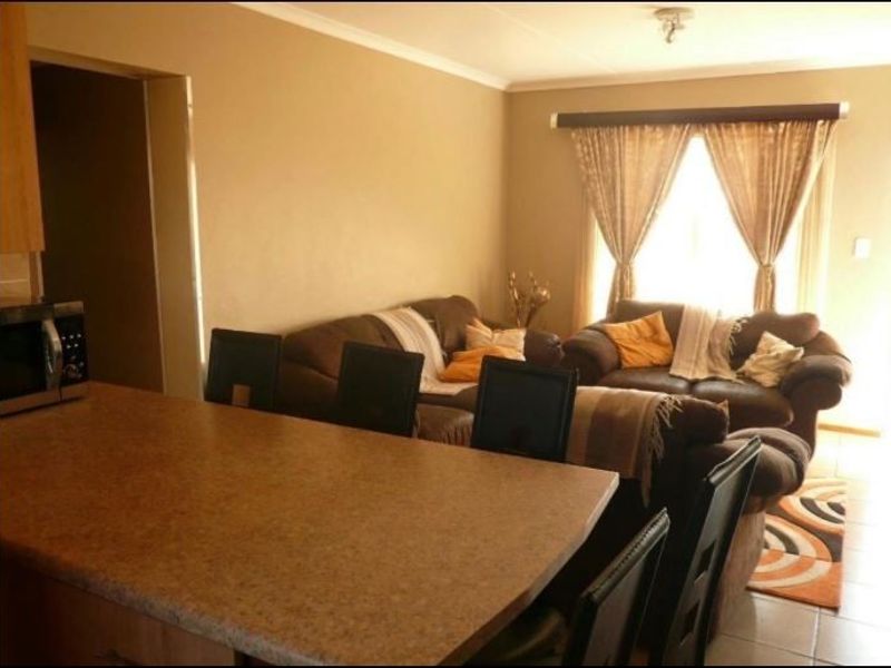 Open plan living area featuring a kitchen island with laminate countertop, tiled flooring, and neutral wall finishes.