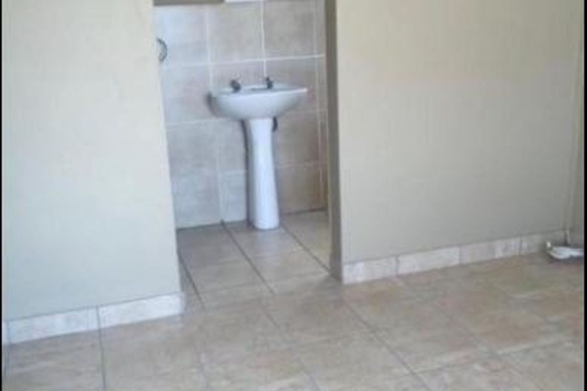A simple, empty bathroom featuring a pedestal basin and neutral tiled flooring and splashback.