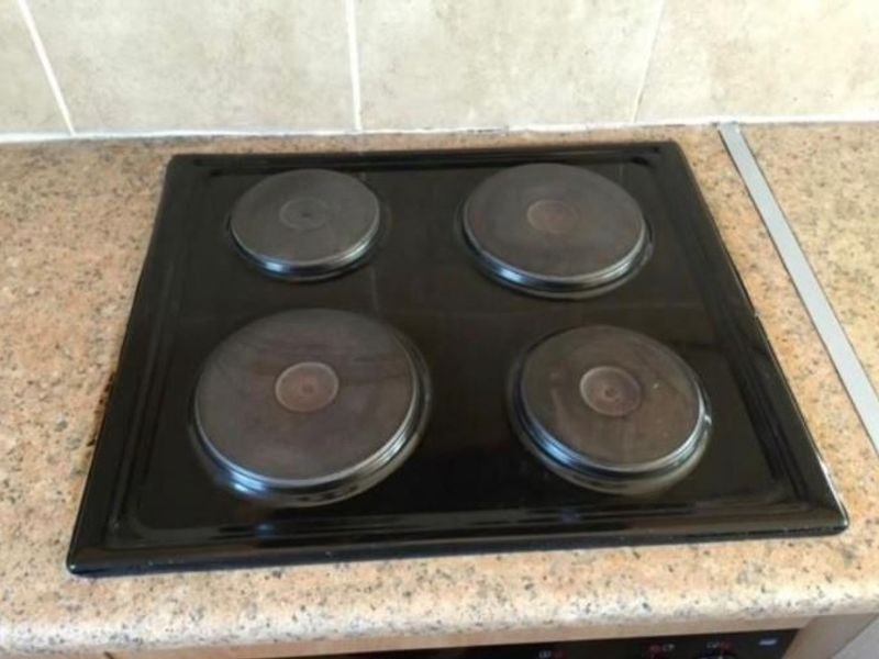 A close-up view of a four-plate electric hob set into a laminate countertop with a tiled splashback.