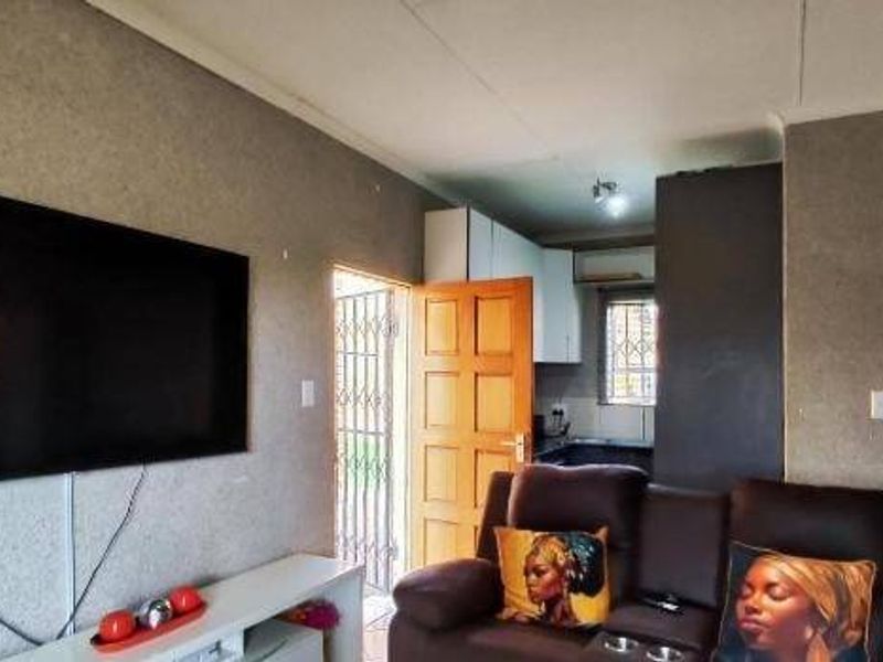 Open plan living area featuring a direct view into the kitchen space with built-in cabinetry and a security gate at the exterior entrance.