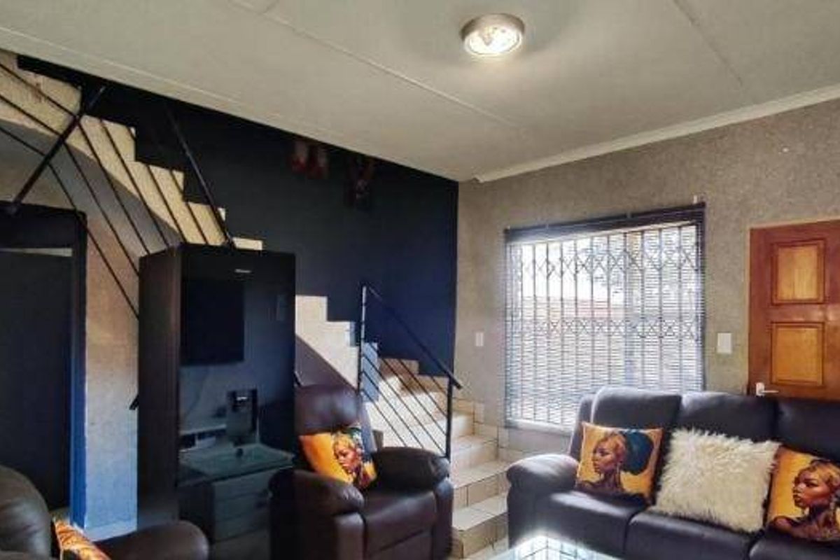 A living room featuring a staircase with a metal balustrade, security gate on the window, and tiled flooring.