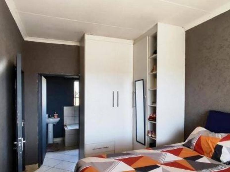 Bedroom featuring built-in wardrobes and direct access to an en-suite bathroom, with dark textured wall finishes.