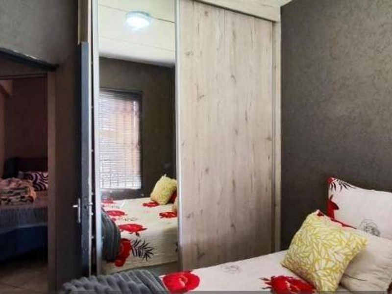 Bedroom featuring dark textured walls and a built-in wardrobe with mirrored sliding doors, providing ample storage and a modern aesthetic.