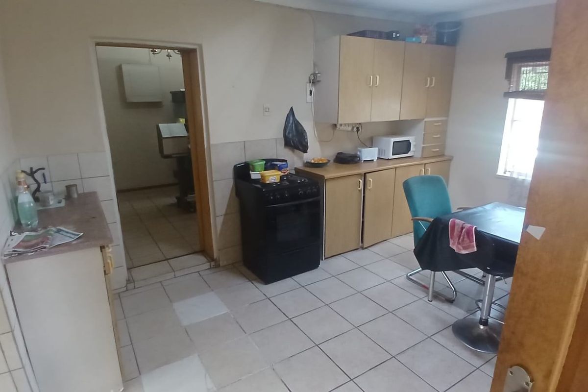 A dated kitchen featuring laminate cabinetry, tiled flooring, and a freestanding stove, offering potential for modernization and renovation.