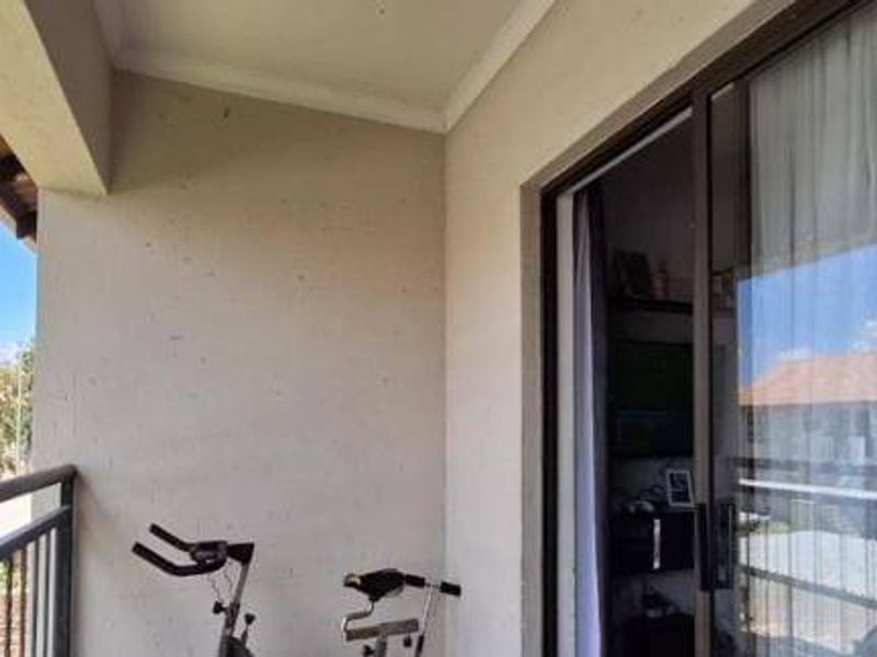 A covered balcony featuring a metal balustrade and sliding glass door access, providing an outdoor extension to the living area.