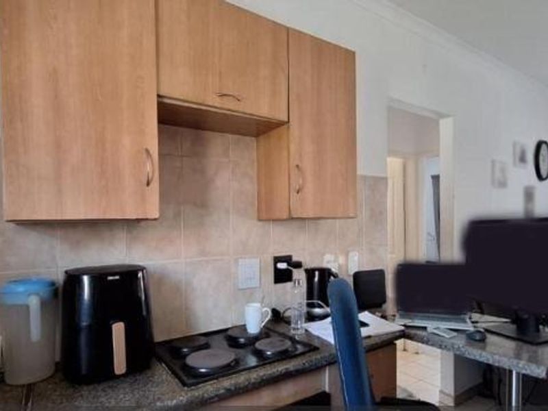 Compact kitchen area featuring laminate cabinetry, a tiled backsplash, and an integrated electric hob with adjacent counter space.