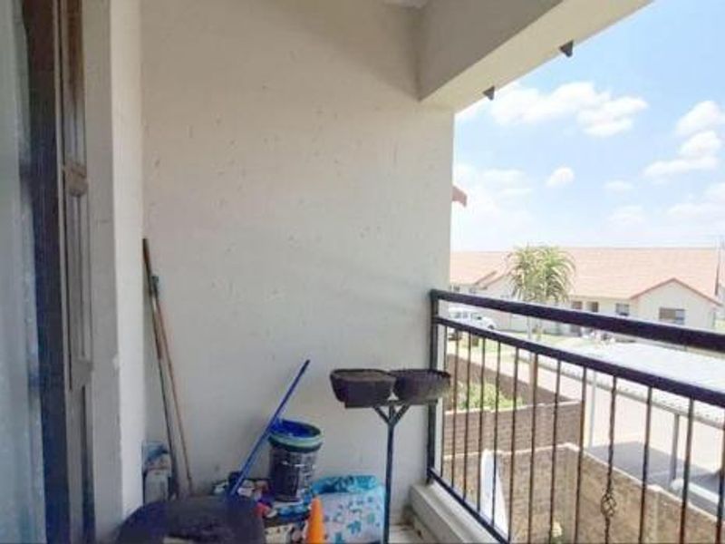 A covered balcony featuring a metal balustrade, offering an open view of the surrounding residential complex.