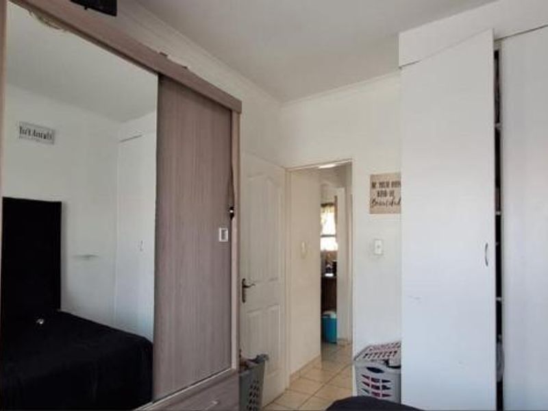 Bedroom featuring extensive built-in storage with mirrored sliding doors and white cabinetry, providing ample closet space and a functional layout.