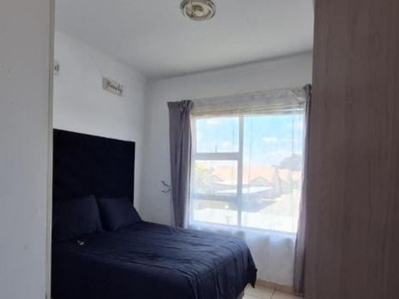 A functional bedroom featuring a built-in wardrobe and a large window providing natural light.