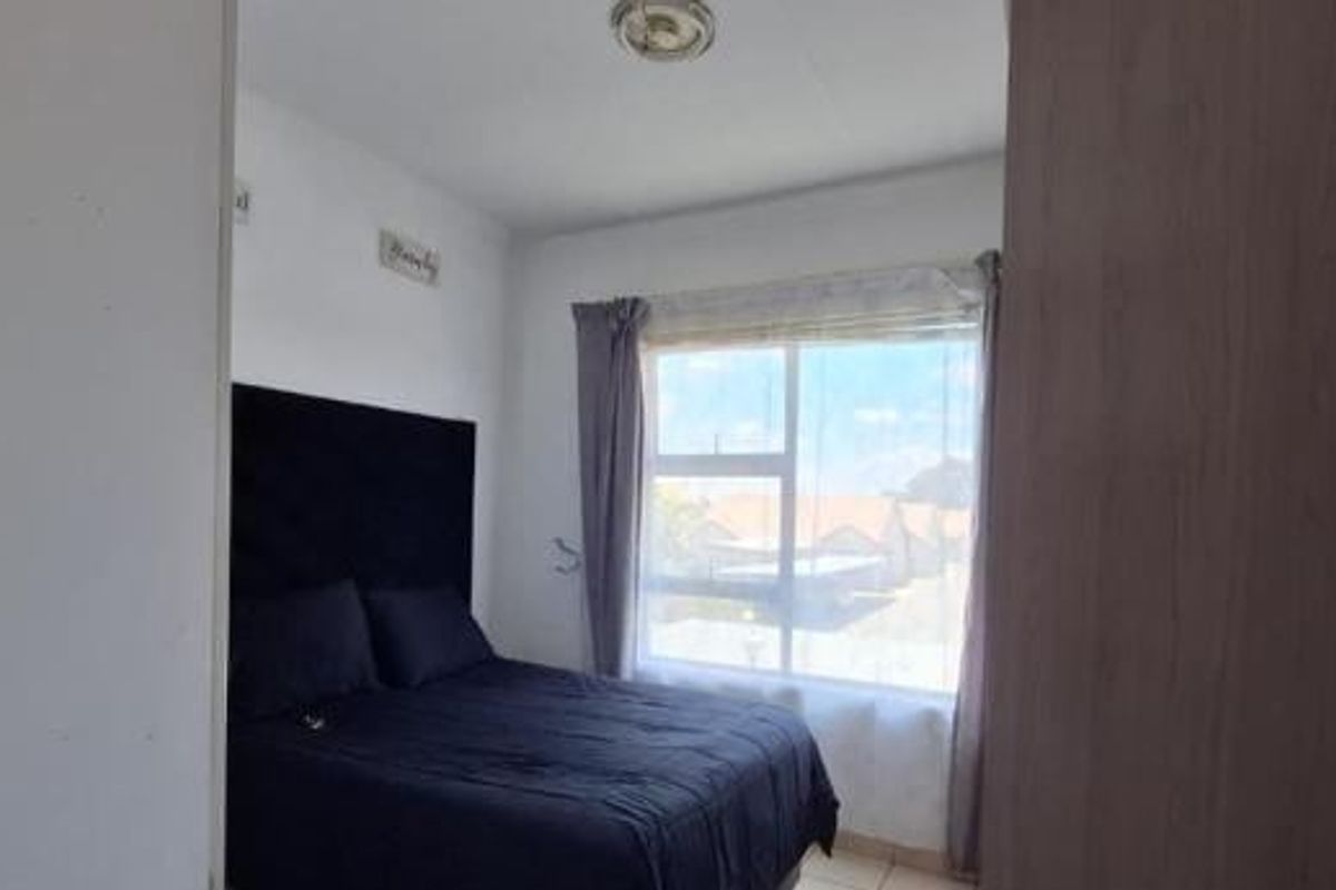 A functional bedroom featuring a built-in wardrobe and a large window providing natural light.