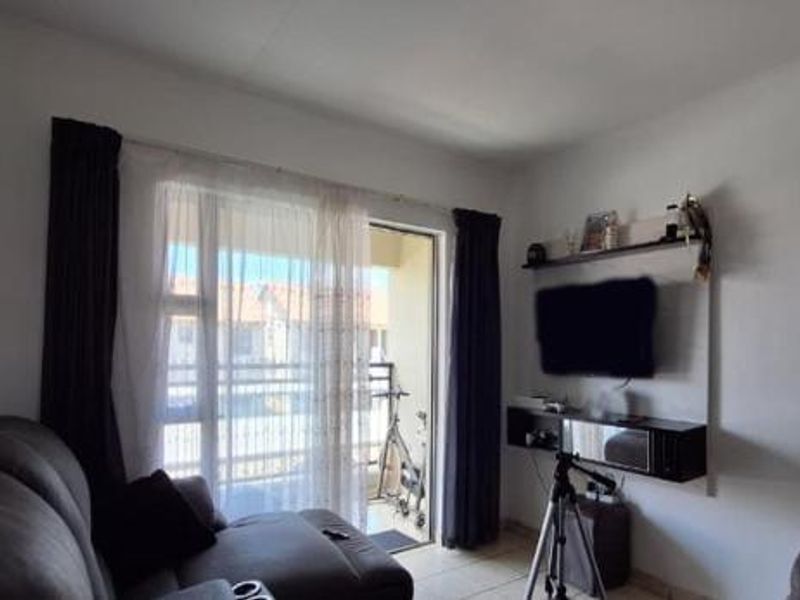 A living room featuring tiled flooring and a sliding glass door providing access to an outdoor balcony area.
