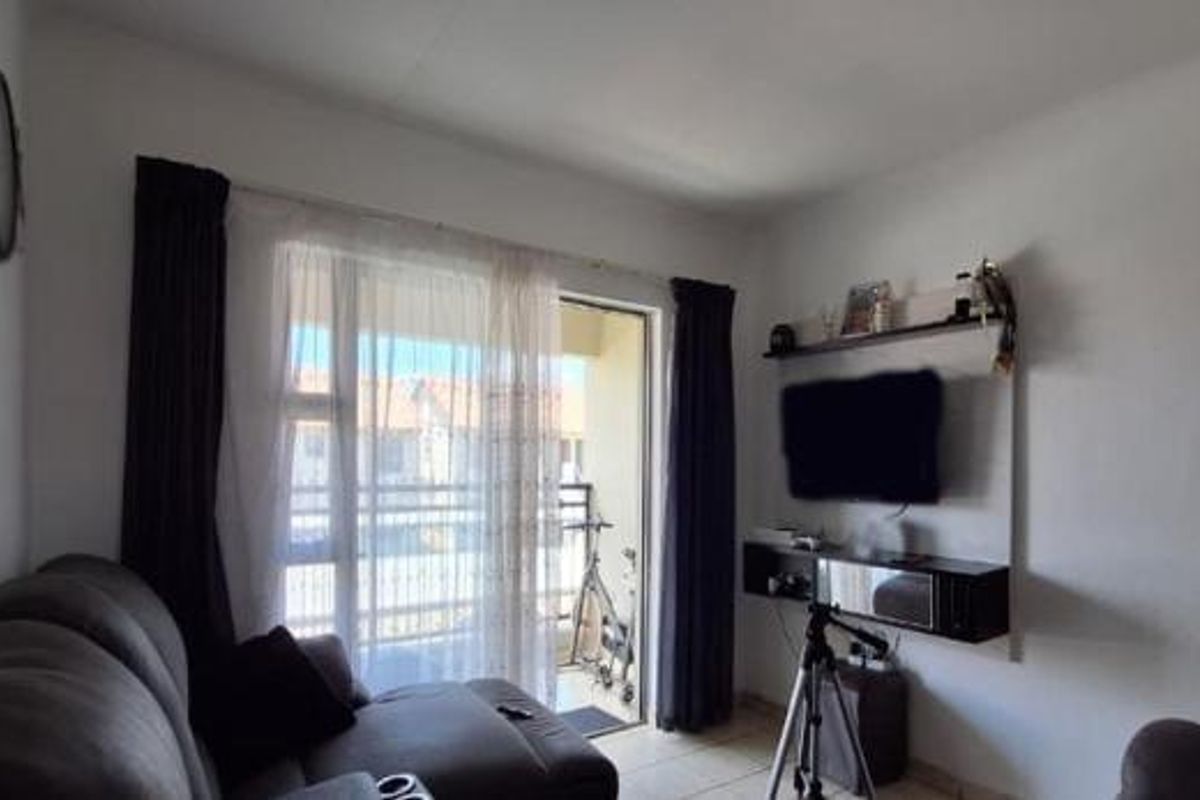 A living room featuring tiled flooring and a sliding glass door providing access to an outdoor balcony area.