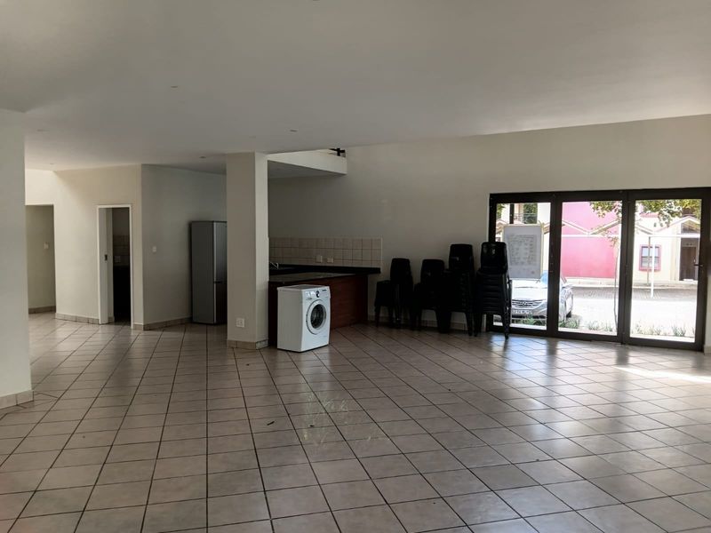Spacious open-plan living area featuring tiled flooring and direct access to the exterior through large sliding glass doors.