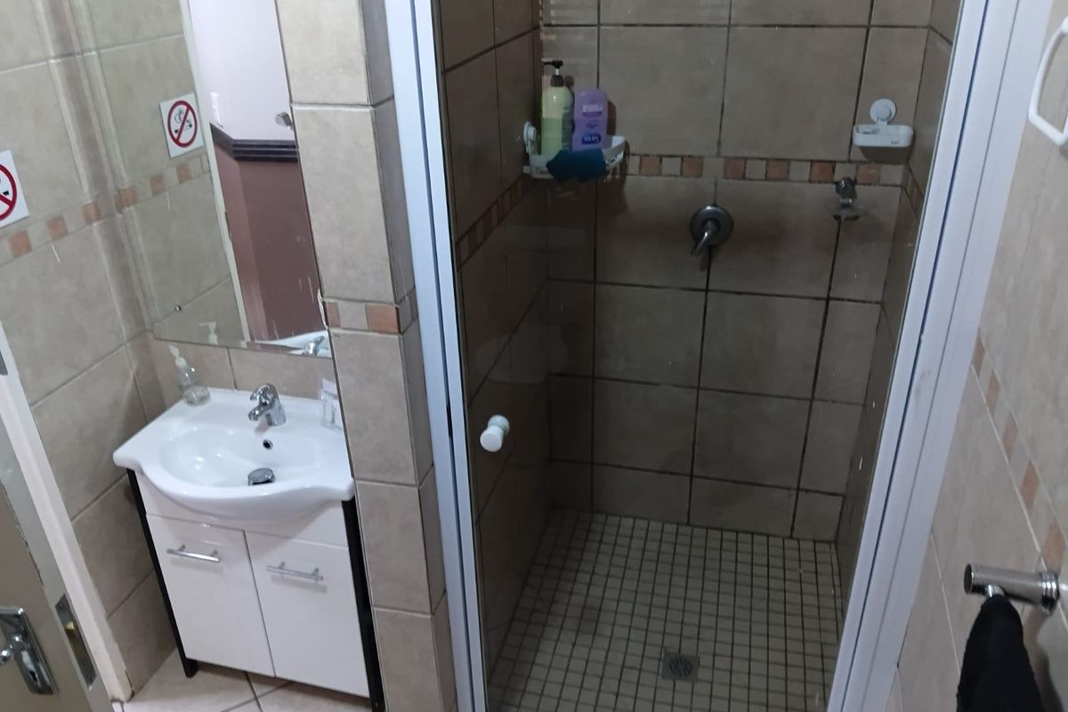 A functional bathroom featuring a tiled shower enclosure, a vanity cabinet with a basin, and wall-mounted mirror.