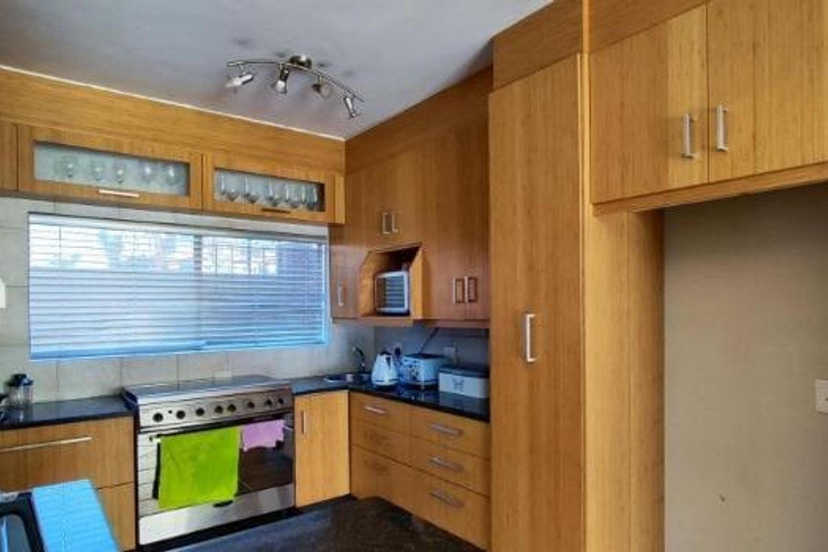 A functional kitchen featuring light wood-toned cabinetry, a stainless steel gas stove, tiled backsplash, and dedicated space for a refrigerator.