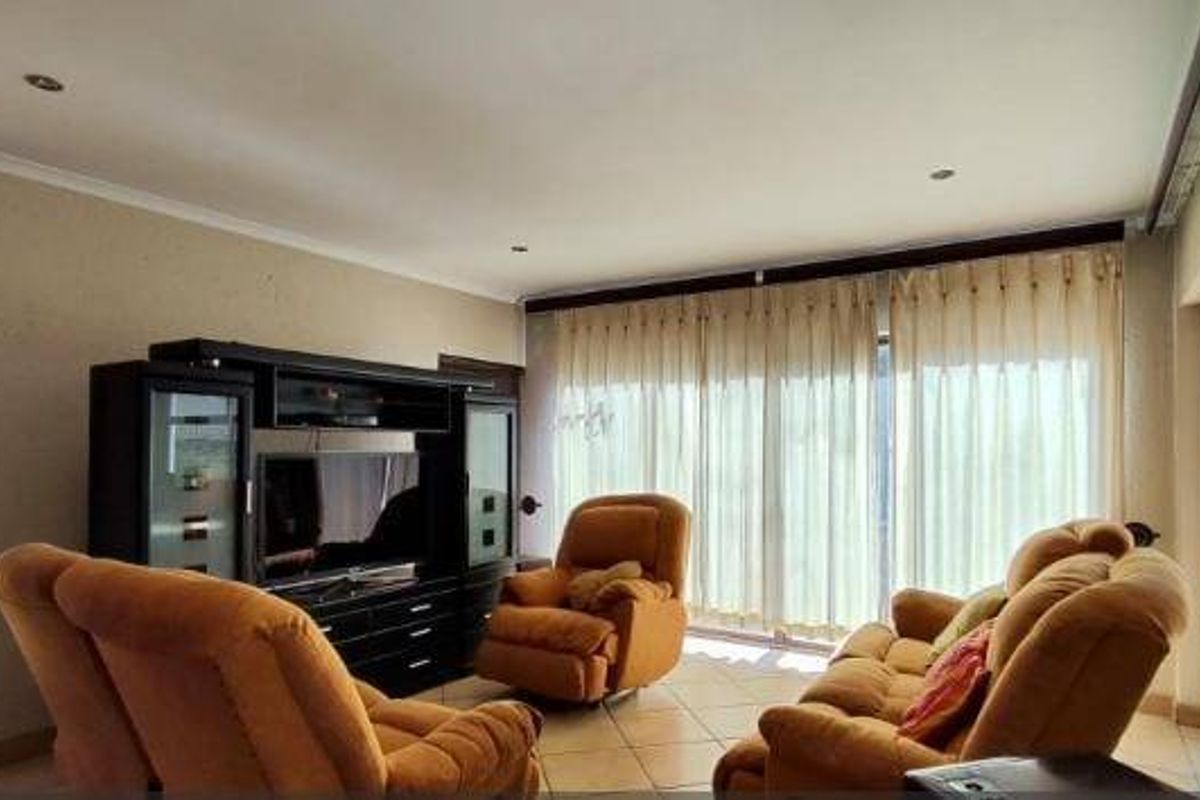 A spacious living room featuring tiled flooring, recessed downlighting, and large sliding glass doors that provide access to the outdoor area.