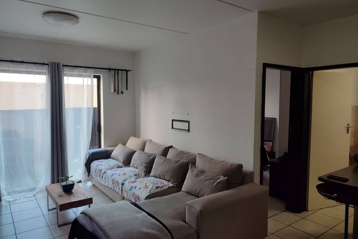 A living room area featuring tiled flooring and a sliding glass door providing access to an outdoor space.