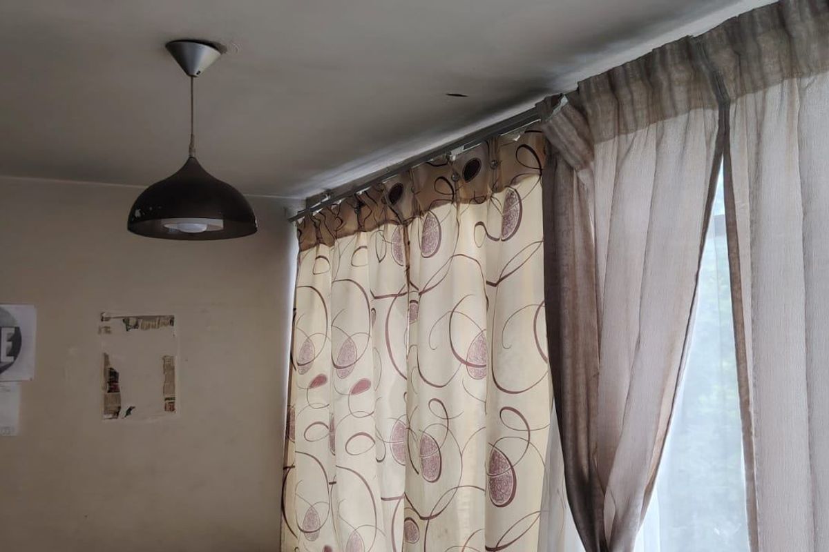 A view of a room corner featuring a pendant light fixture and window curtains.