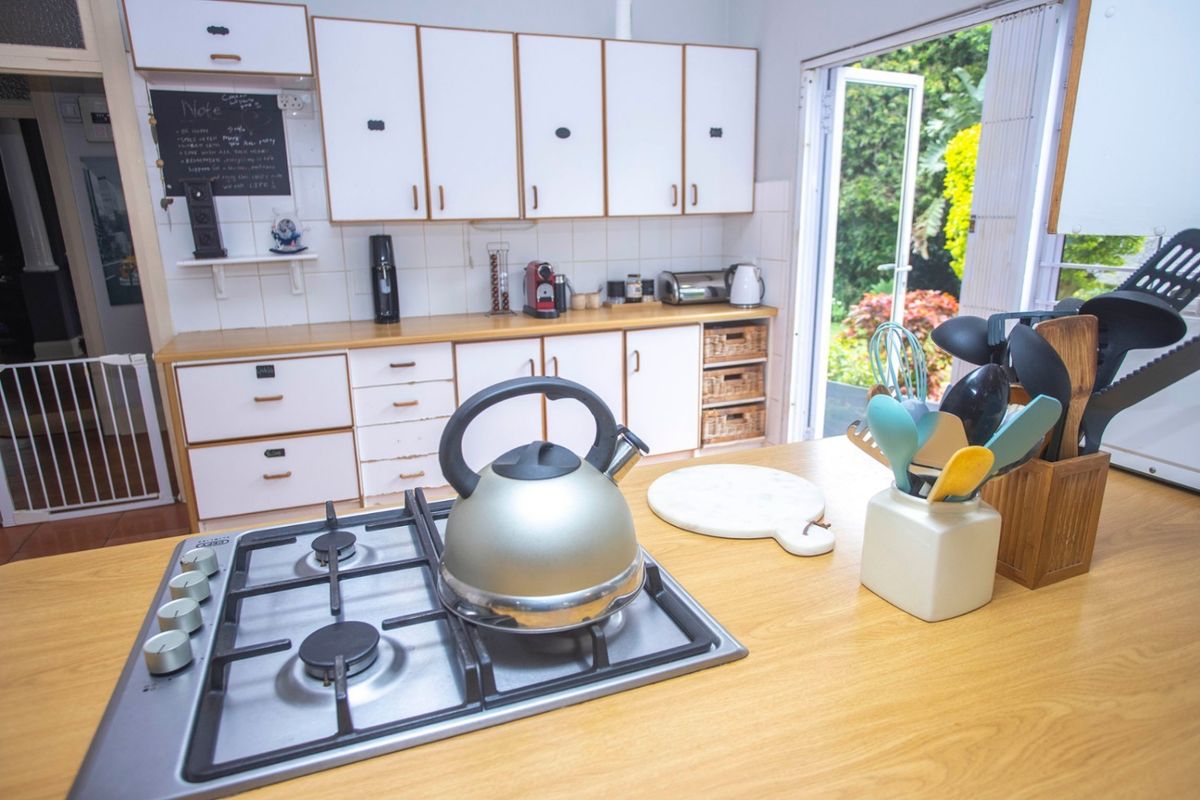 A functional kitchen featuring a central island with a built-in gas hob, ample cabinetry, and direct access to the rear garden.