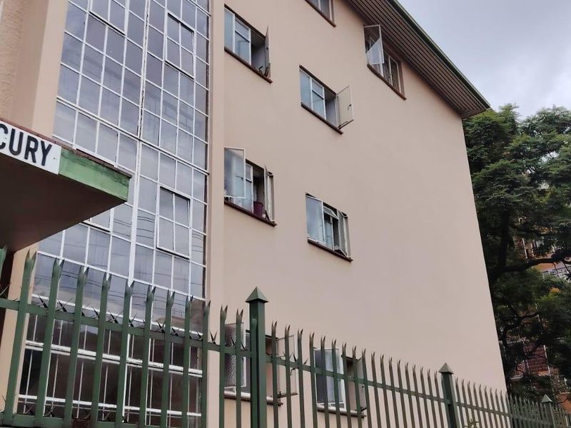 Exterior view of the Mercury apartment building facade featuring multi-story windows and perimeter security fencing.