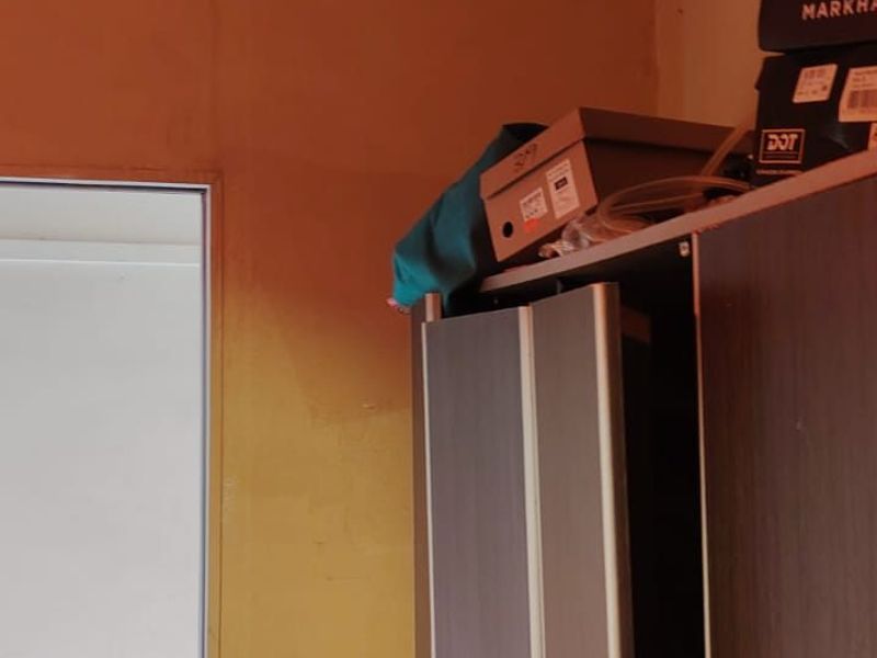 A bedroom interior featuring a built-in wardrobe with unfinished wall surfaces requiring painting and cosmetic repair.