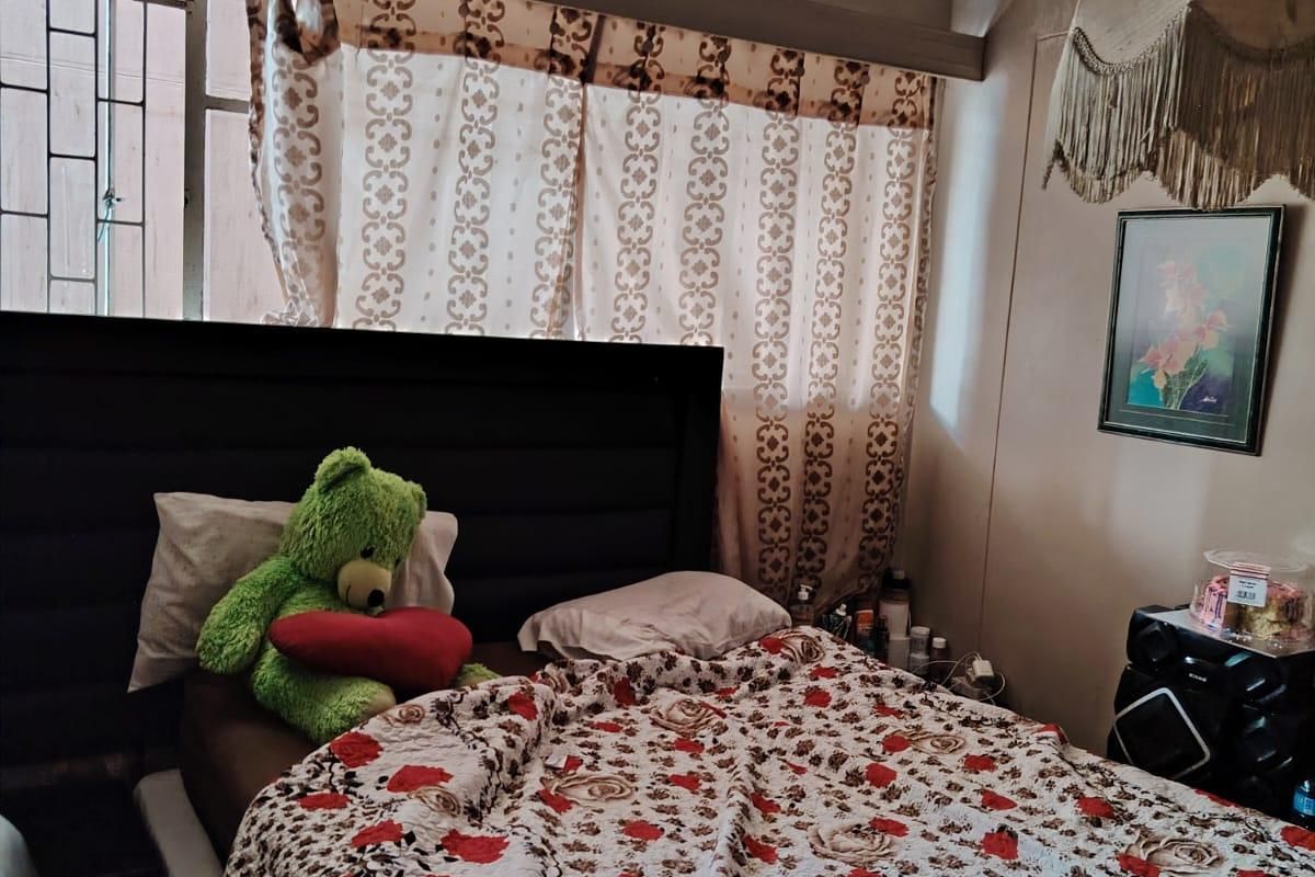 A bedroom featuring security bars on the window, requiring cosmetic updates to the ceiling and wall finishes to improve the overall aesthetic.