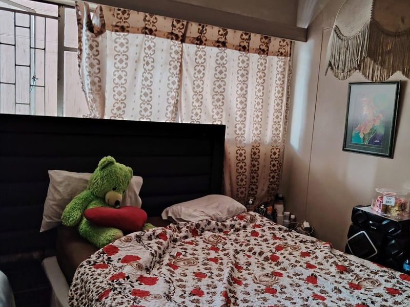 A bedroom featuring security bars on the window, requiring cosmetic updates to the ceiling and wall finishes to improve the overall aesthetic.