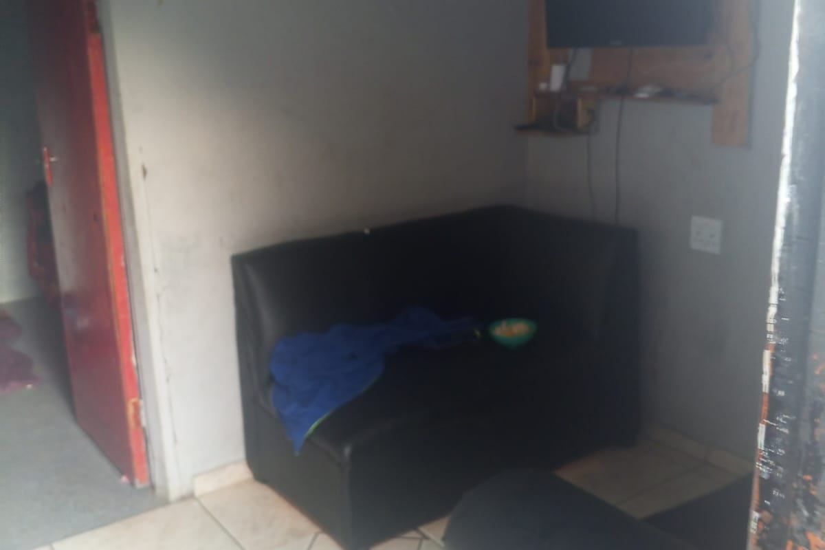 A compact living area featuring tiled flooring and a wall-mounted television setup, requiring cosmetic updates to improve the overall aesthetic.