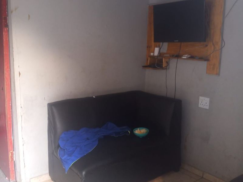 A living area featuring tiled flooring and wall-mounted television infrastructure, requiring cosmetic updates to the wall finishes.