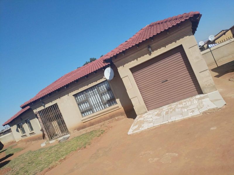 Front exterior view of a single-story house featuring a tiled roof, integrated garage with a roller door, and security fixtures on windows and doors.