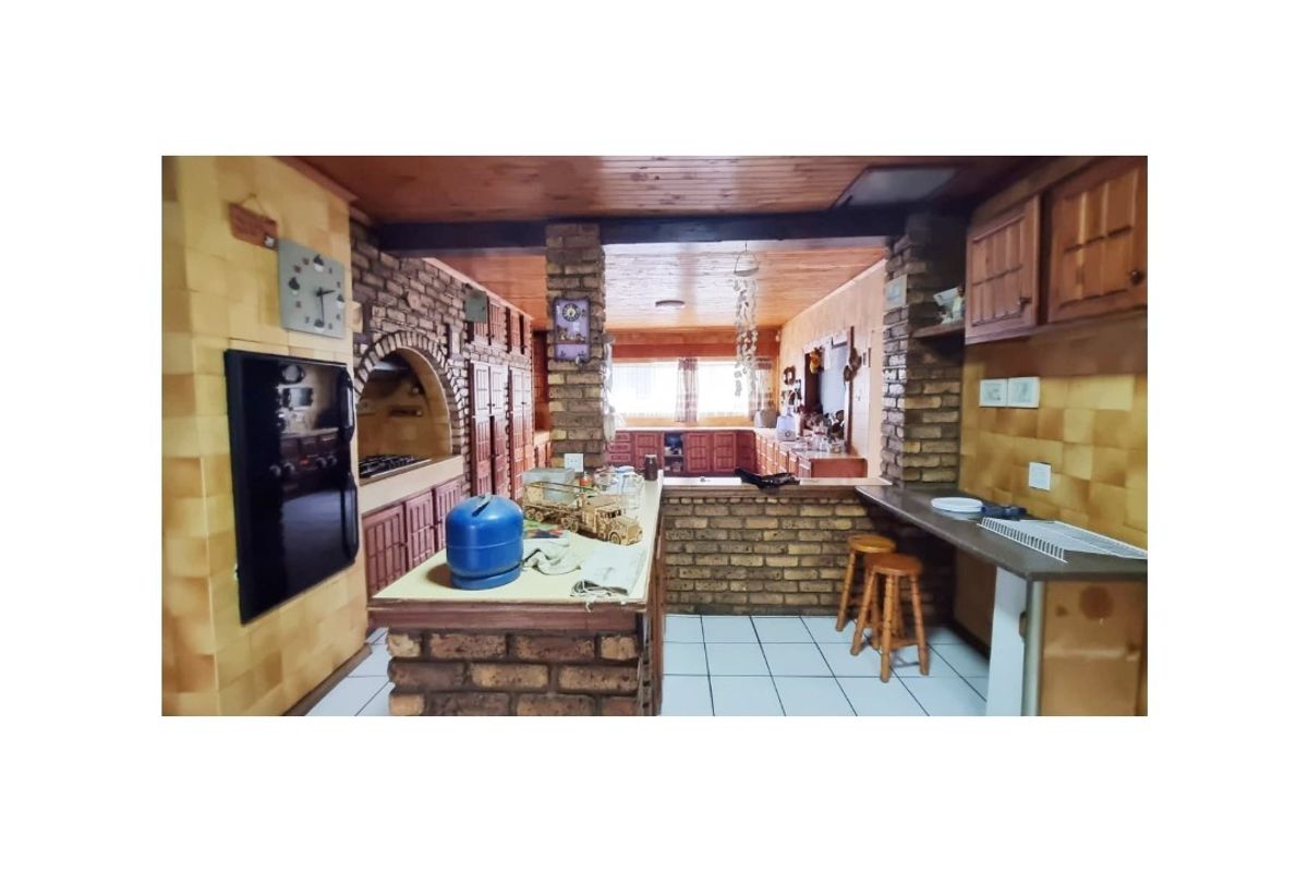 A rustic kitchen featuring extensive brickwork, wooden cabinetry, a breakfast bar, and a built-in oven area with a traditional arched design.