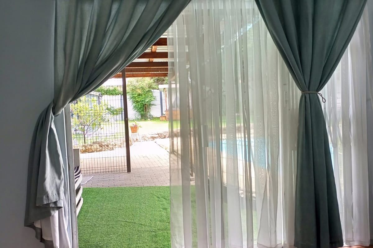 A living room area featuring tiled flooring and a large sliding glass door providing direct access to the outdoor patio and pool area.