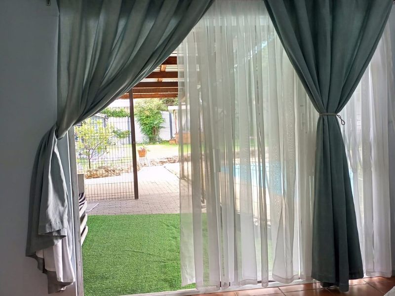 A living room area featuring tiled flooring and a large sliding glass door providing direct access to the outdoor patio and pool area.