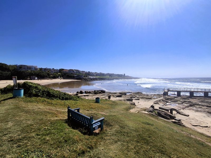A scenic coastal view overlooking the beach, rocky shoreline, and ocean, highlighting the property's proximity to the coastline.