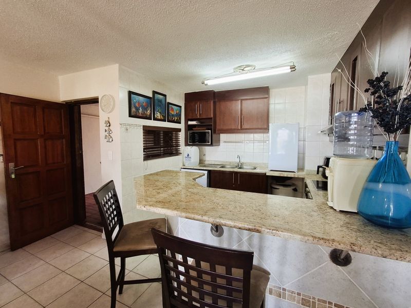 A functional kitchen featuring a granite breakfast bar, dark wood cabinetry, and ceramic tile finishes, offering a practical layout for daily use.