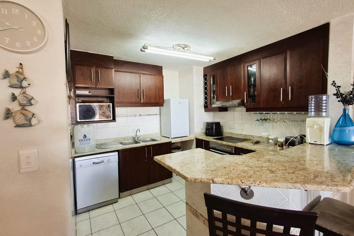 Functional kitchen featuring dark wood cabinetry, granite countertops, a breakfast bar, and tiled finishes, providing a practical layout for daily meal preparation.