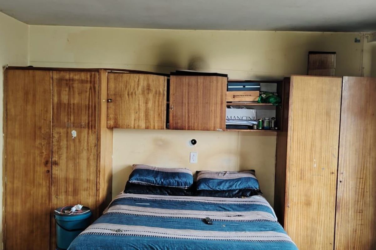 Bedroom featuring extensive built-in wooden cabinetry and overhead storage units, requiring cosmetic updates to the walls and ceiling finishes.
