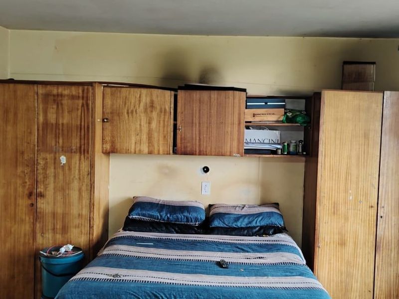 Bedroom featuring extensive built-in wooden cabinetry and overhead storage units, requiring cosmetic updates to the walls and ceiling finishes.