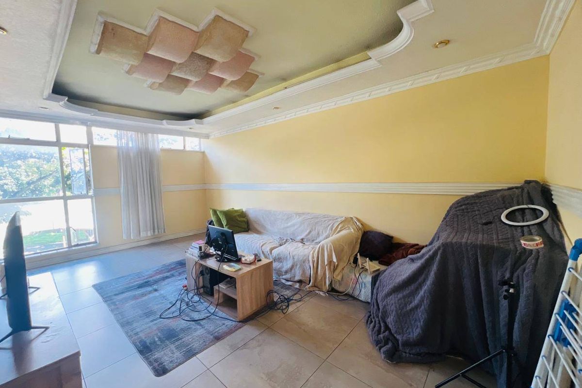 A living room featuring tiled flooring, large windows for natural light, and decorative ceiling molding.