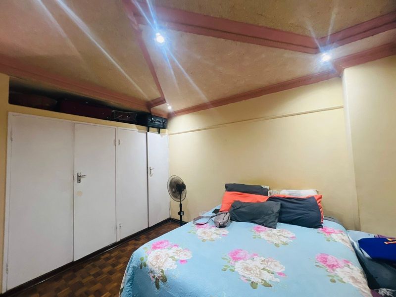 A bedroom featuring built-in wardrobes, parquet flooring, and a unique vaulted ceiling design with recessed lighting.