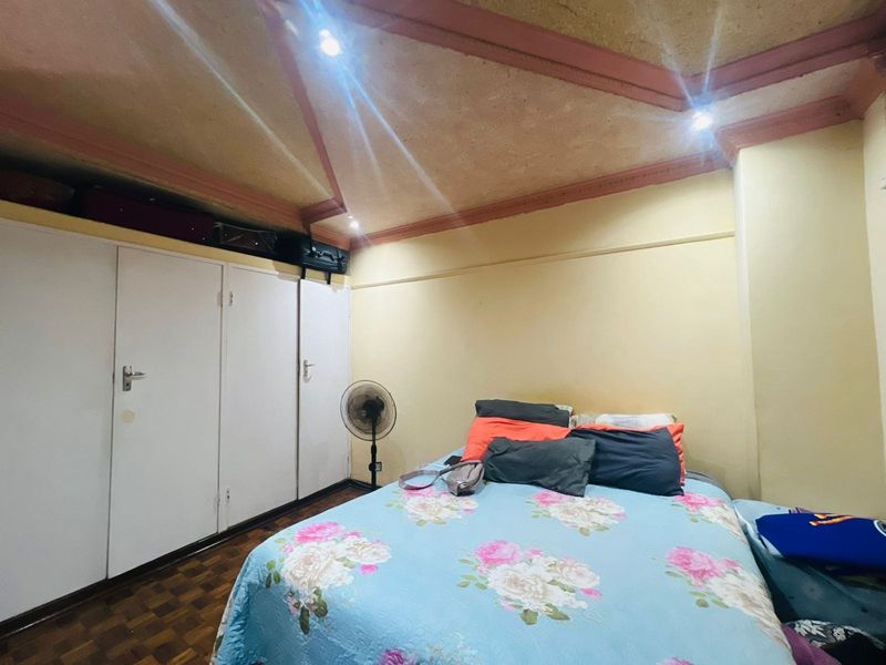 A bedroom featuring built-in white cabinetry, parquet flooring, and a vaulted ceiling with recessed lighting.