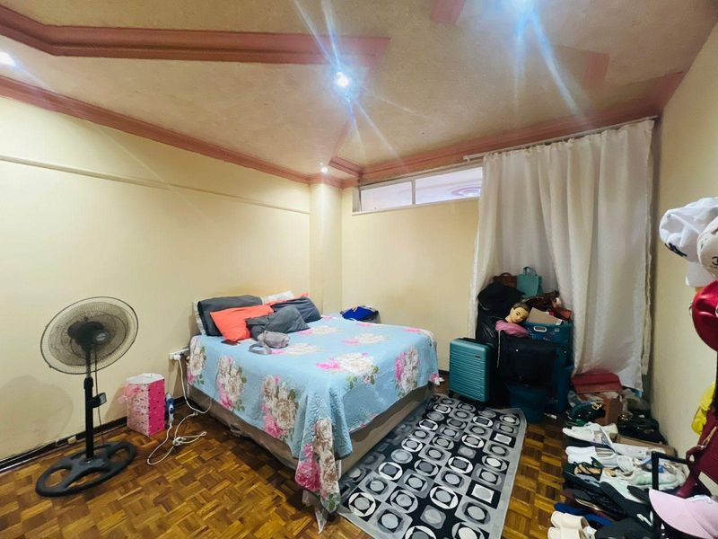 A bedroom featuring parquet flooring and a tray ceiling with decorative trim, offering a functional space for rest.
