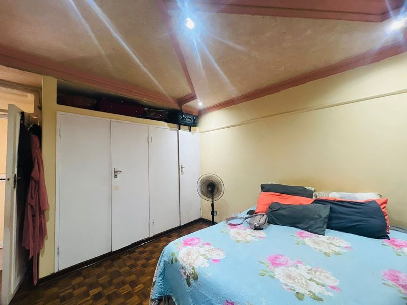 A bedroom featuring built-in wardrobes, parquet flooring, and a vaulted ceiling with recessed lighting.