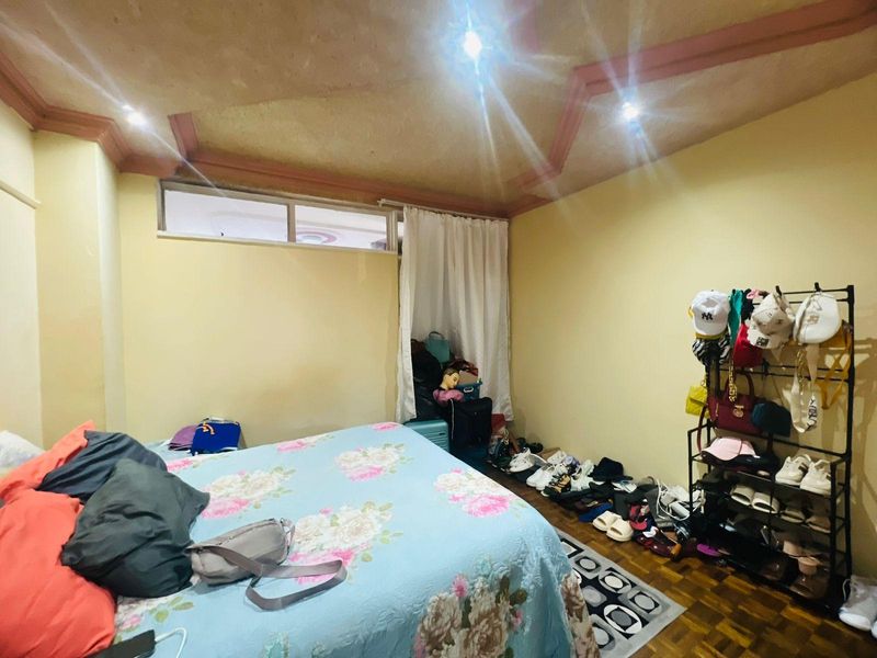 A bedroom featuring parquet flooring, recessed ceiling lighting, and a high-level window, offering a functional space for rest.