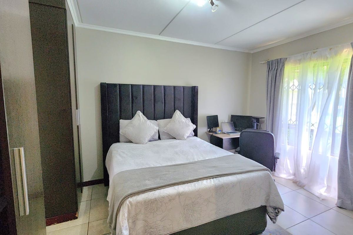A well-maintained bedroom featuring tiled flooring, a built-in wardrobe, and neutral wall finishes with natural light from the window.